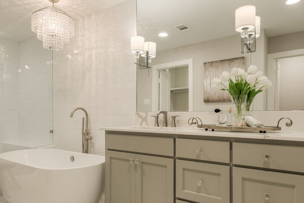 Dallas custom home bathroom with double vanity, wall sconces and custom cabinetry designed by Design by KETI